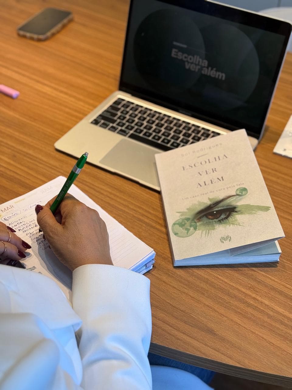 Sol Rodrigues escrevendo com o livro Escolha Ver Além